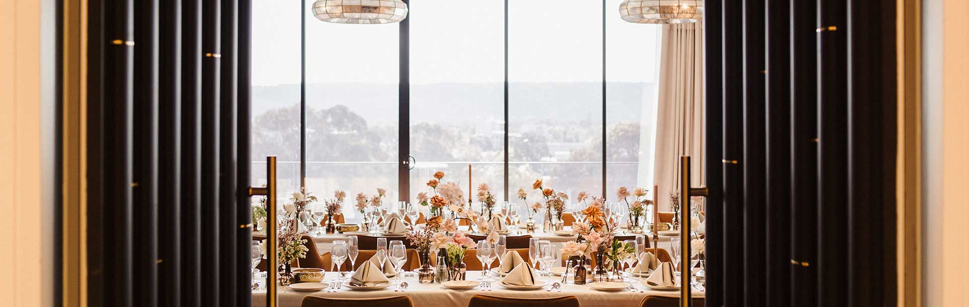 View out window of mountains foregrouns floral styled event room through grand doors