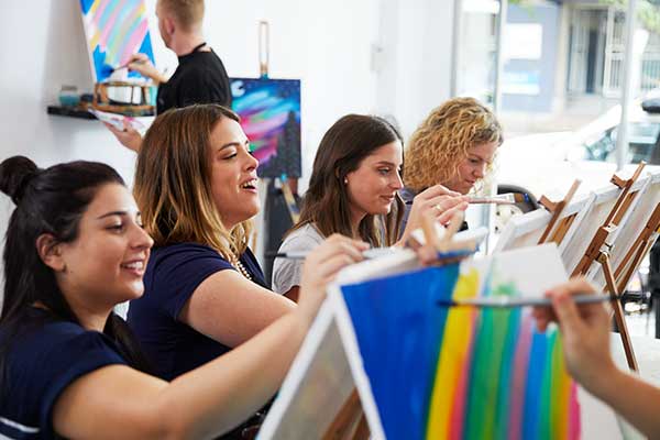 Women in art class painting at easels
