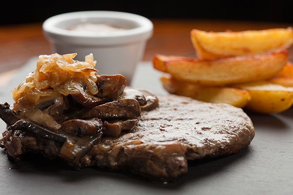 A steak with onions and wedges