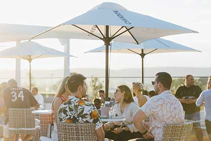Two couples at roof top bar sitting at a table under a sun umbrella