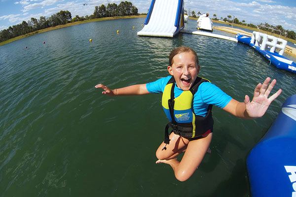 Girl jumping into water off an inflatable runway at Cables Aqua Park Cables aqua park
