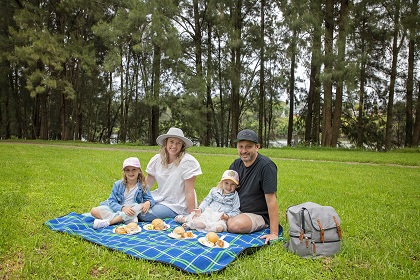 Young family enjoying a picnic on a blanket at Tench Reserve