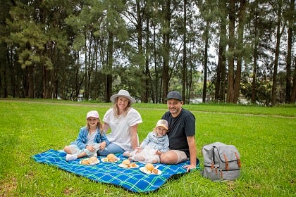 Young family enjoying a picnic on a blanket at Tench Reserve