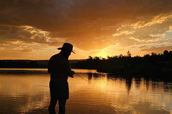 man fishing on river sunset backdrop