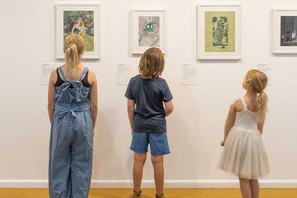 three kids looking at art on wall