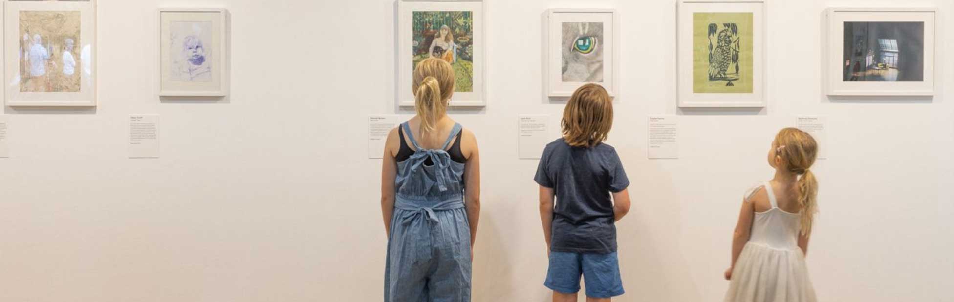 three kids looking at art on wall