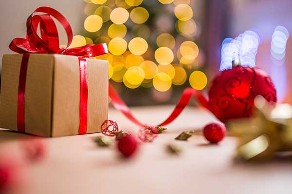 Brown gift box with red ribbon surrounded by christmas lights