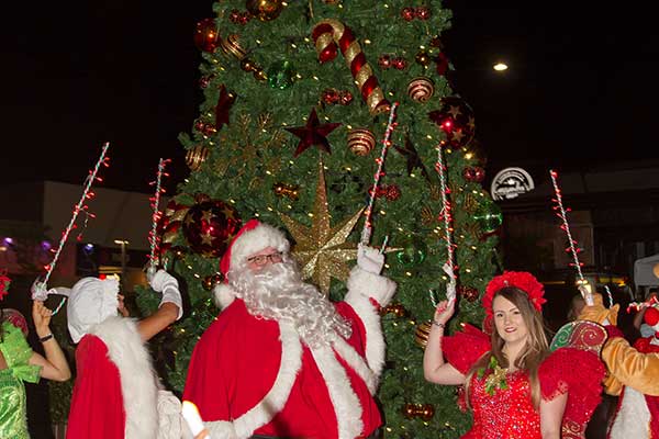 Characters and family posing for photo around Christmas tree