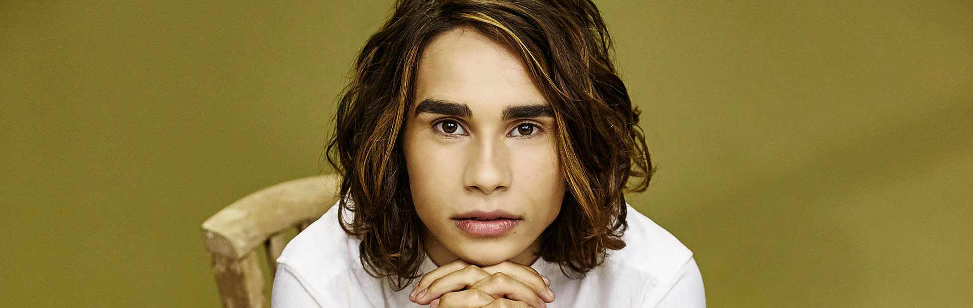 Isaiah Firebrace sitting on chair chin sitting on his hands