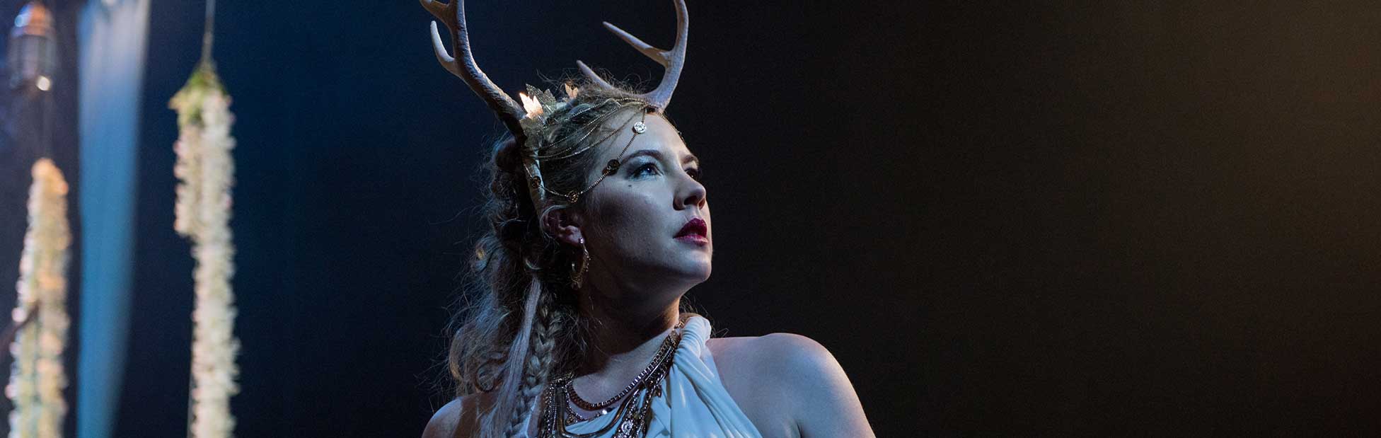 Female actor wearing antlers looking into distance