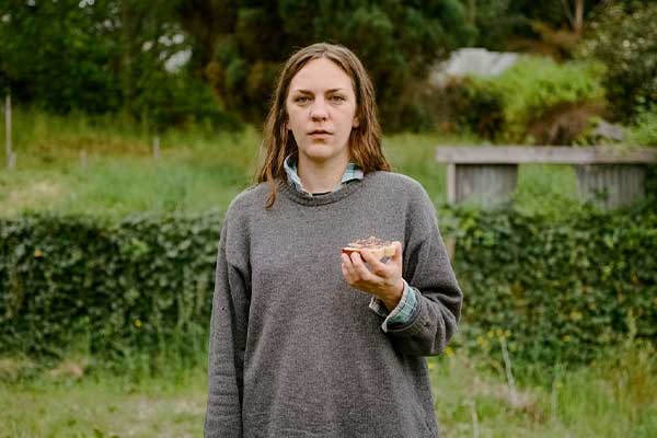 Woman standing in garden in grey jumper holding toast