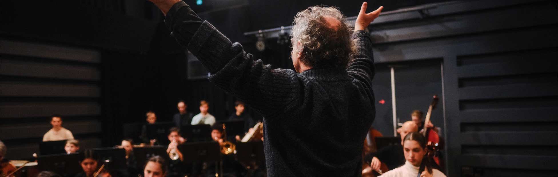 conductor with hands up in front of orchestra