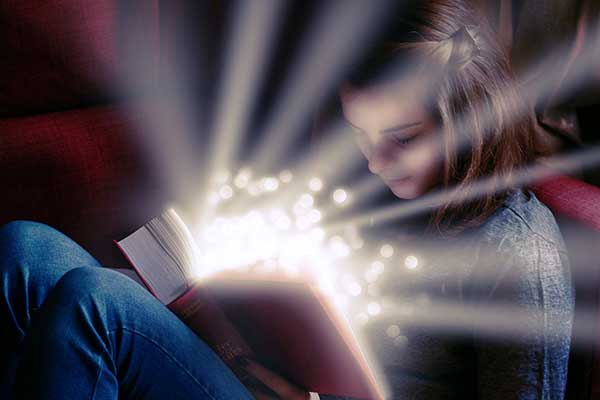 Girl reading a book with light coming out