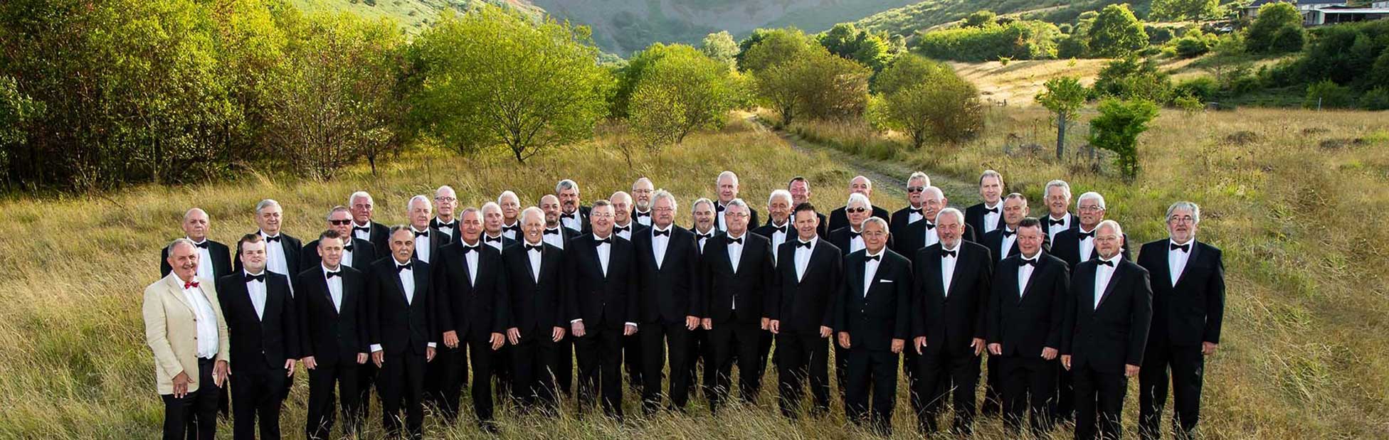 Large group of men in Tuxedos standing in mountains