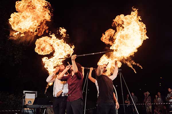 Men playing instruments with fire behind them 