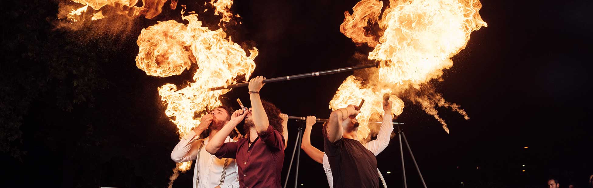 Men playing instruments with fire behind them 