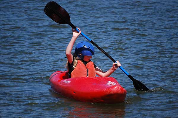 Teenage girl paddling in red kayak