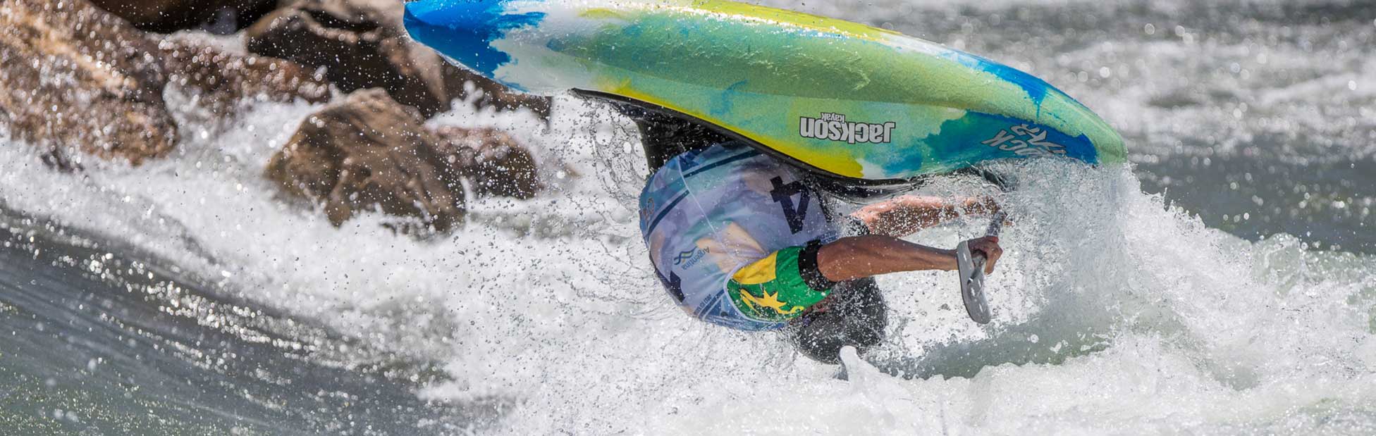 Male competitor in kayak mid somersault on the whitewater