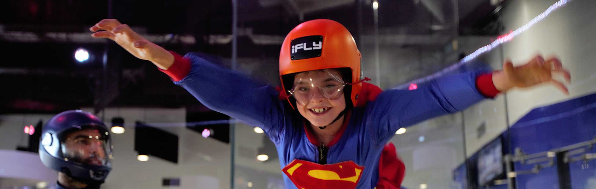 Child indoor skydiving wearing superman outfit