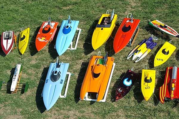 Colourful model boats in rows on green grass