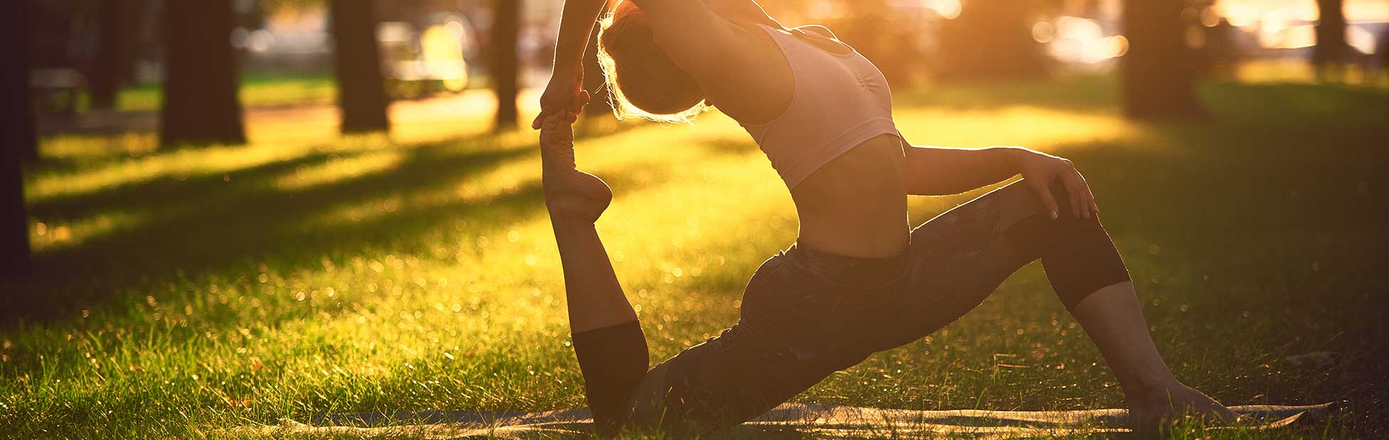 Woman in yoga pose with sunrise behind her