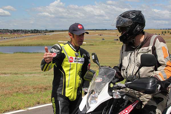 Instructor talking to motorcyclist on side of track