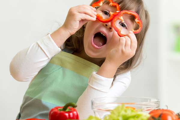 girl holding capsicum to her eyes like glasses