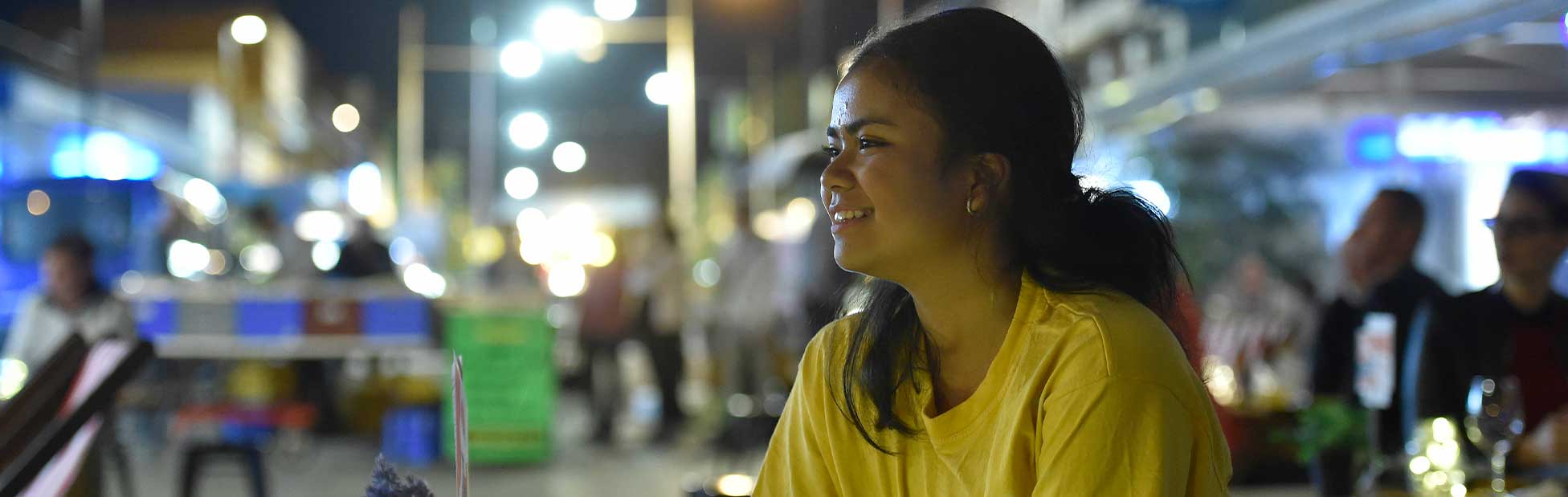 Woman on lit street smiling