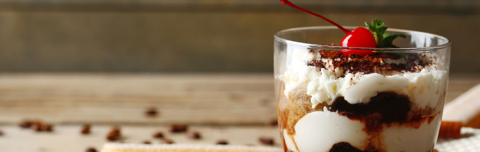 A chocolate and cream desert in a glass with a cherry on top