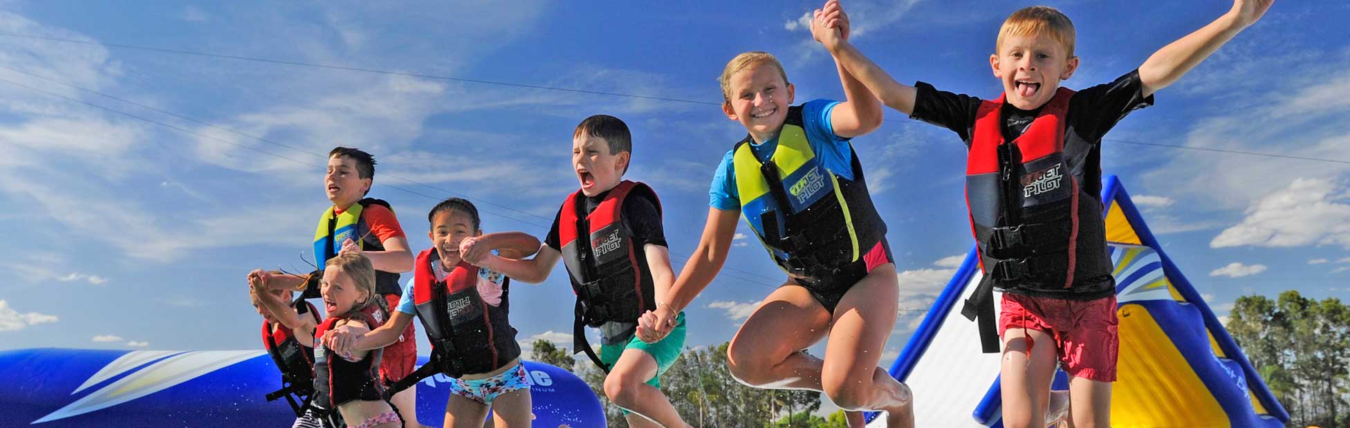 A group of kids jumping into the water off a slide