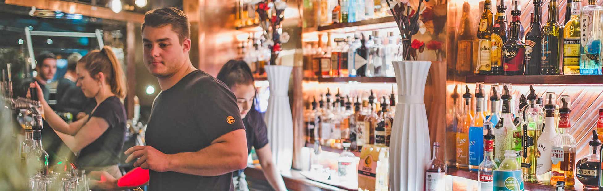 A group of bar tenders serving drinks at a bar