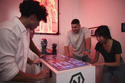 Three people working together to solve a puzzle to escape an escape room