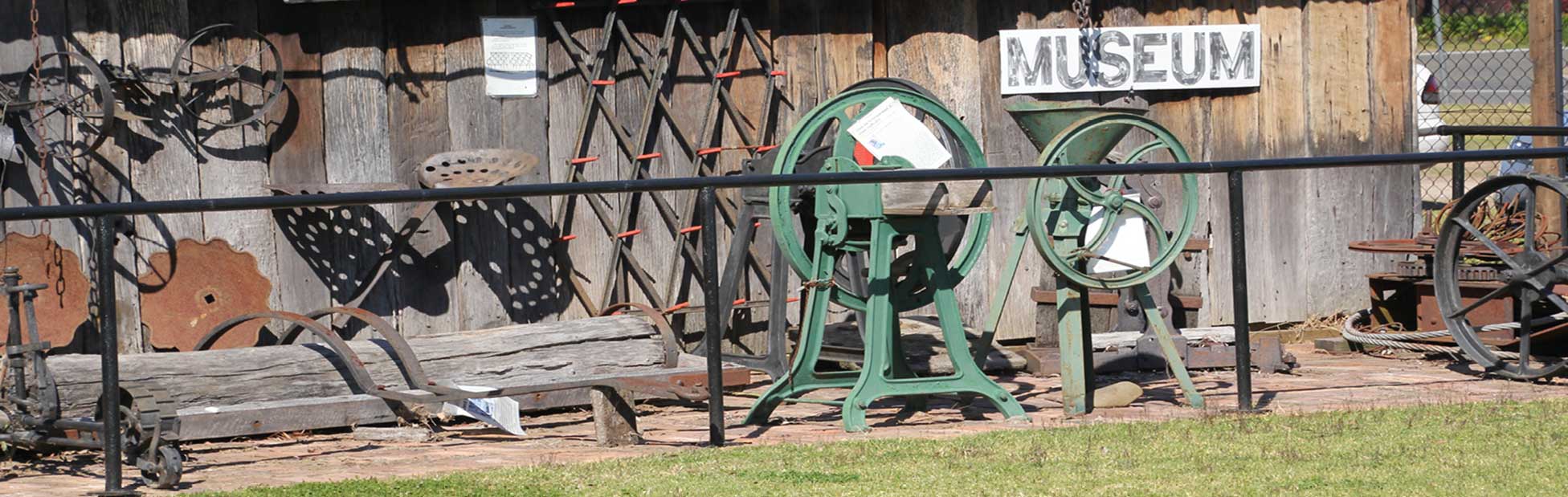 An assortment of old farming tools outside a shed