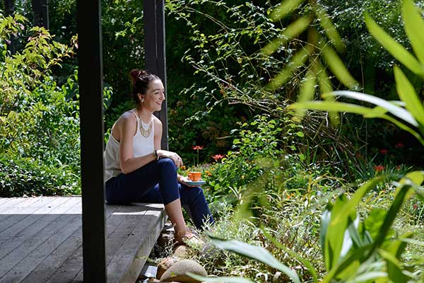 Young lady sitting on a verandah surrounded by a lucious green garden