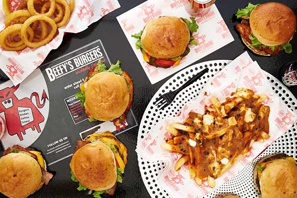 Table laid out with burgers, gravy chips and onion rings