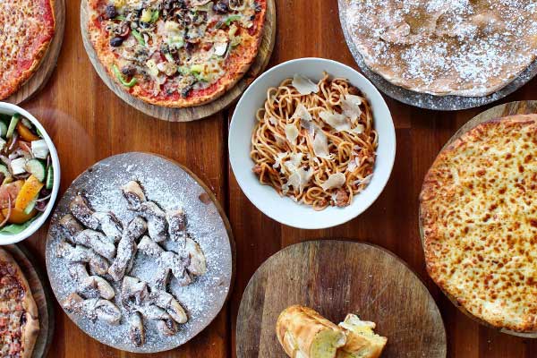 Pizza pasta and salad on rustic wood table top