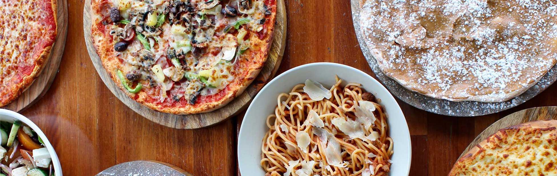 Pizza pasta and salad on rustic wood table top