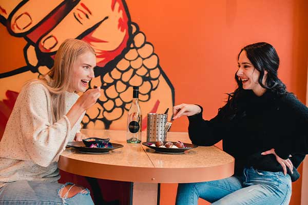 Two women at table talking and eating