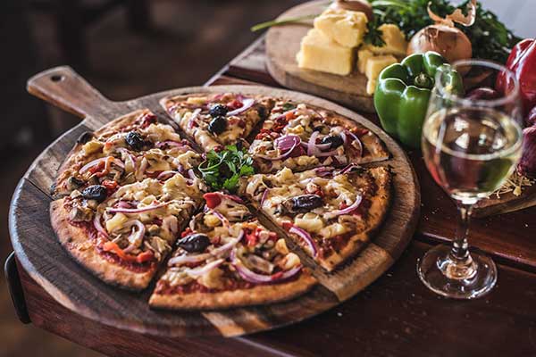 A close up of a supreme pizza on a wooden serving dish