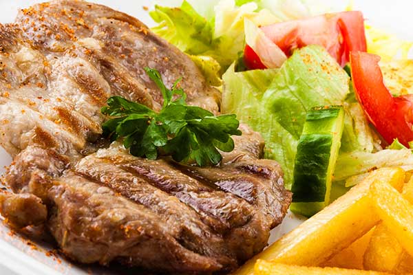 A steak with salad and chips on a plate