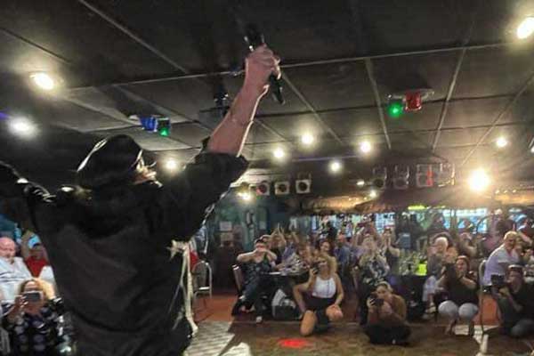 Man on stage with hands up crowd watching and clapping