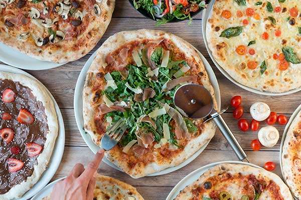 Table full of Italian style assorted pizzas