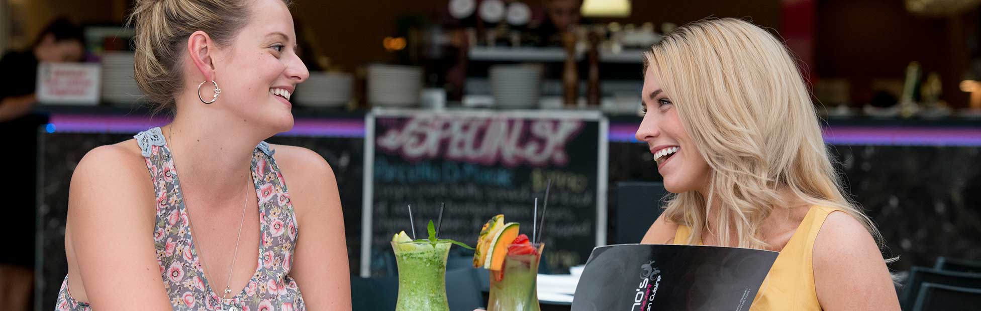 Two young girls enjoying drinks and food at a cafe