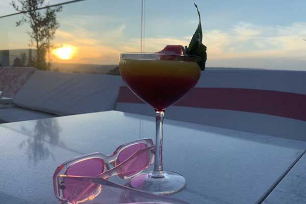 cocktail on edge of roof top pool at sunset