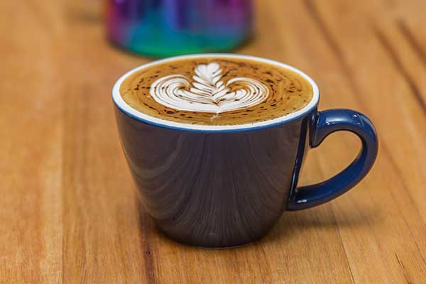 Coffee with spectacular barista art in blue cup