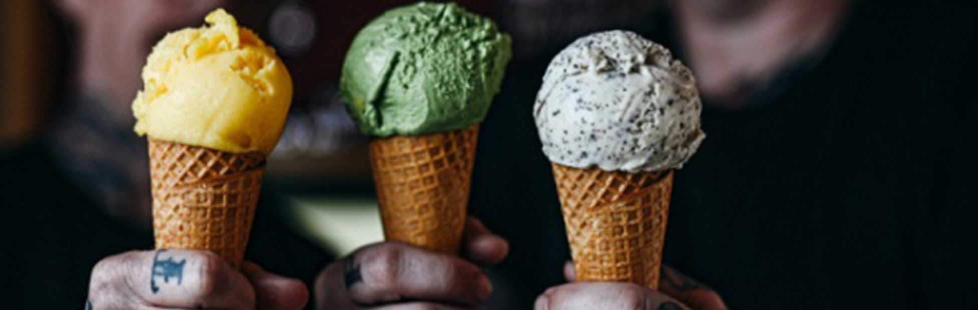 tattooed hands holding cones of gelato