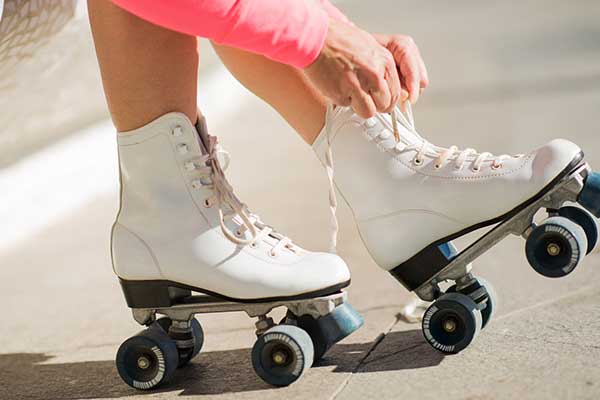 Closeup of roller skate shoelaces being tied up by a pair of hands