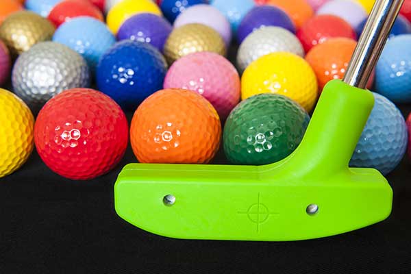 A bunch of different coloured golf balls and a golf putter