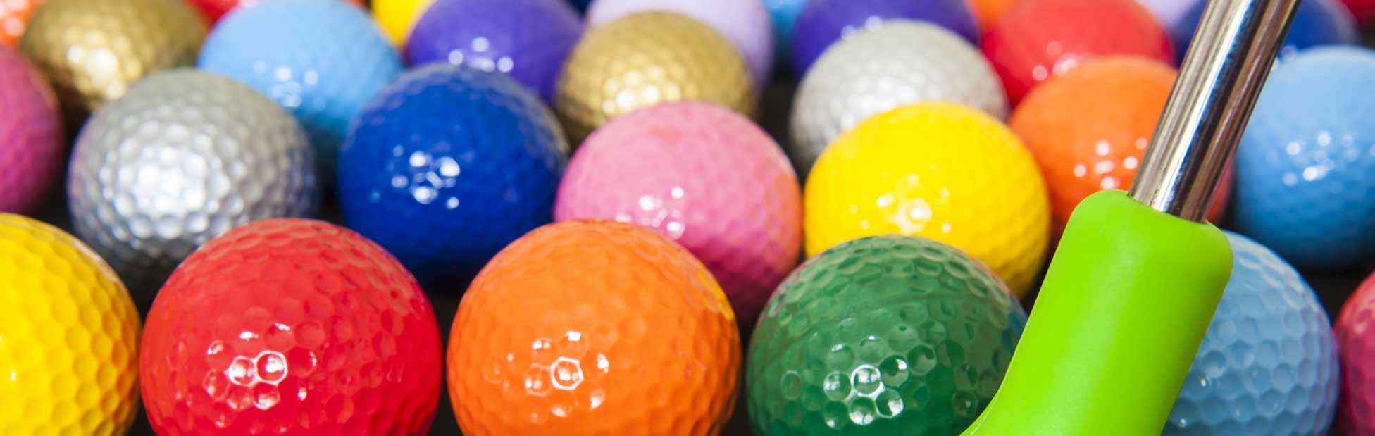 A bunch of different coloured golf balls and a golf putter