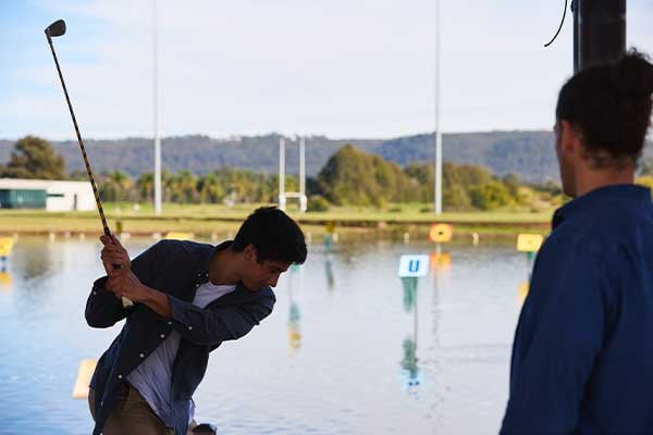 people hitting balls into aqua driving range